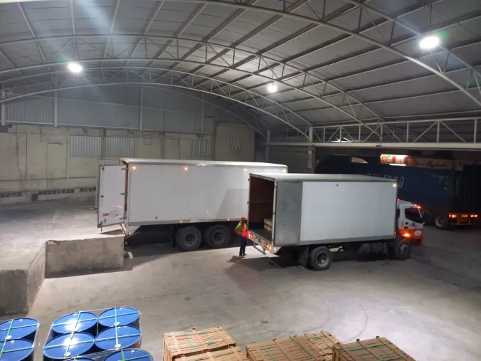 Dos unidades cargando en el andén interior del almacén, con personal supervisando la maniobra