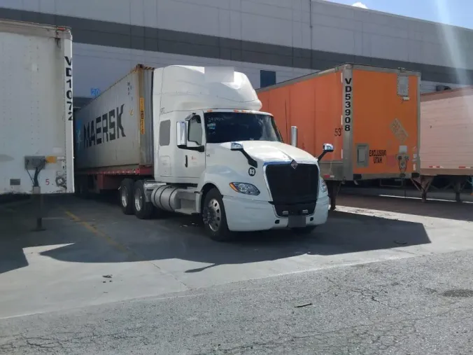 Tractocamión de Flety con un contenedor marítimo, estacionado entre cajas secas en el andén de un centro de distribución